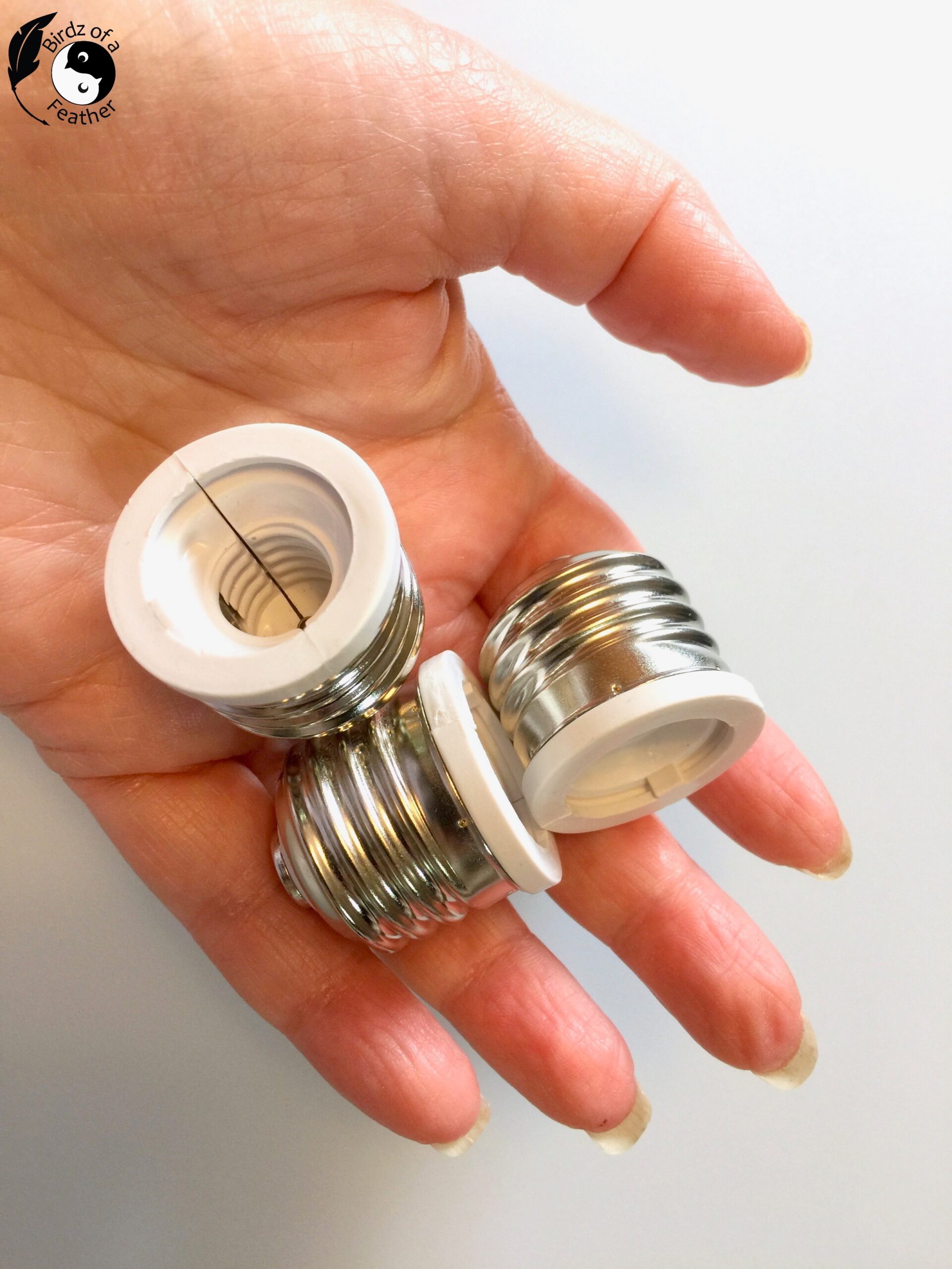 Hand holding standard base adapters used in plastic packaging for cement planter molds