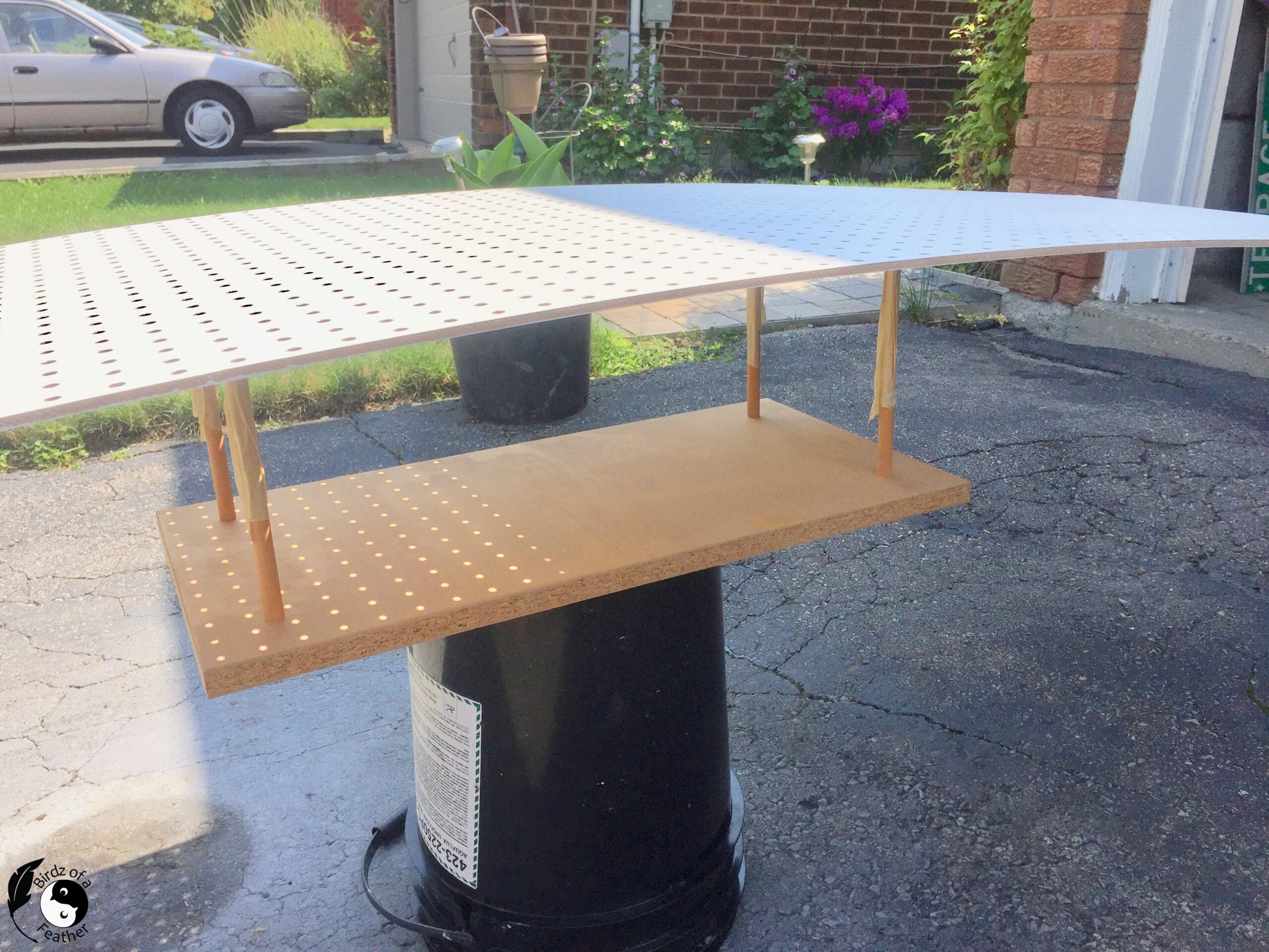 Large pegboard sitting on top of a paint jig made with wood and dowels
