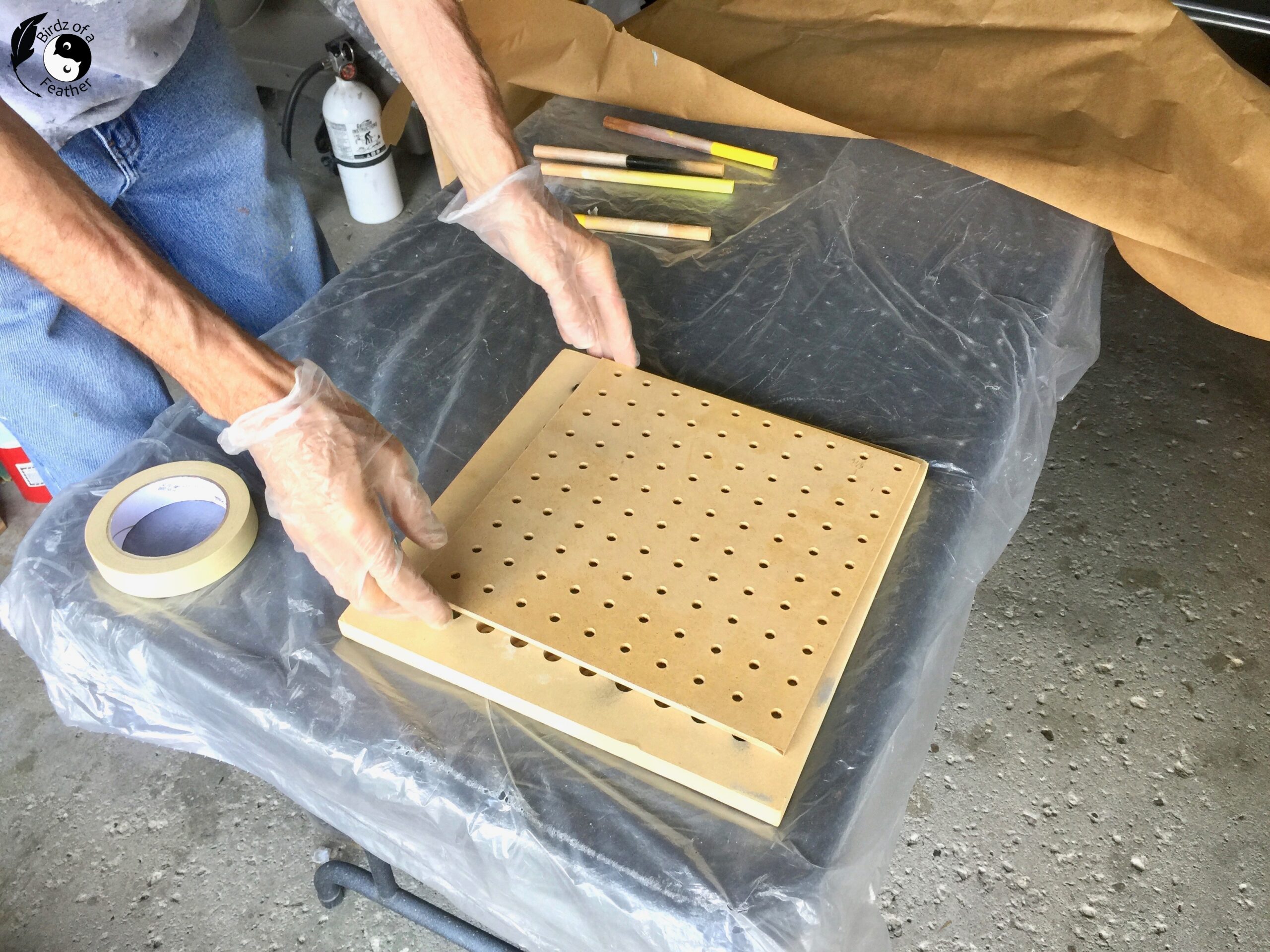 Pegboard positioned over small paint jig for spray painting