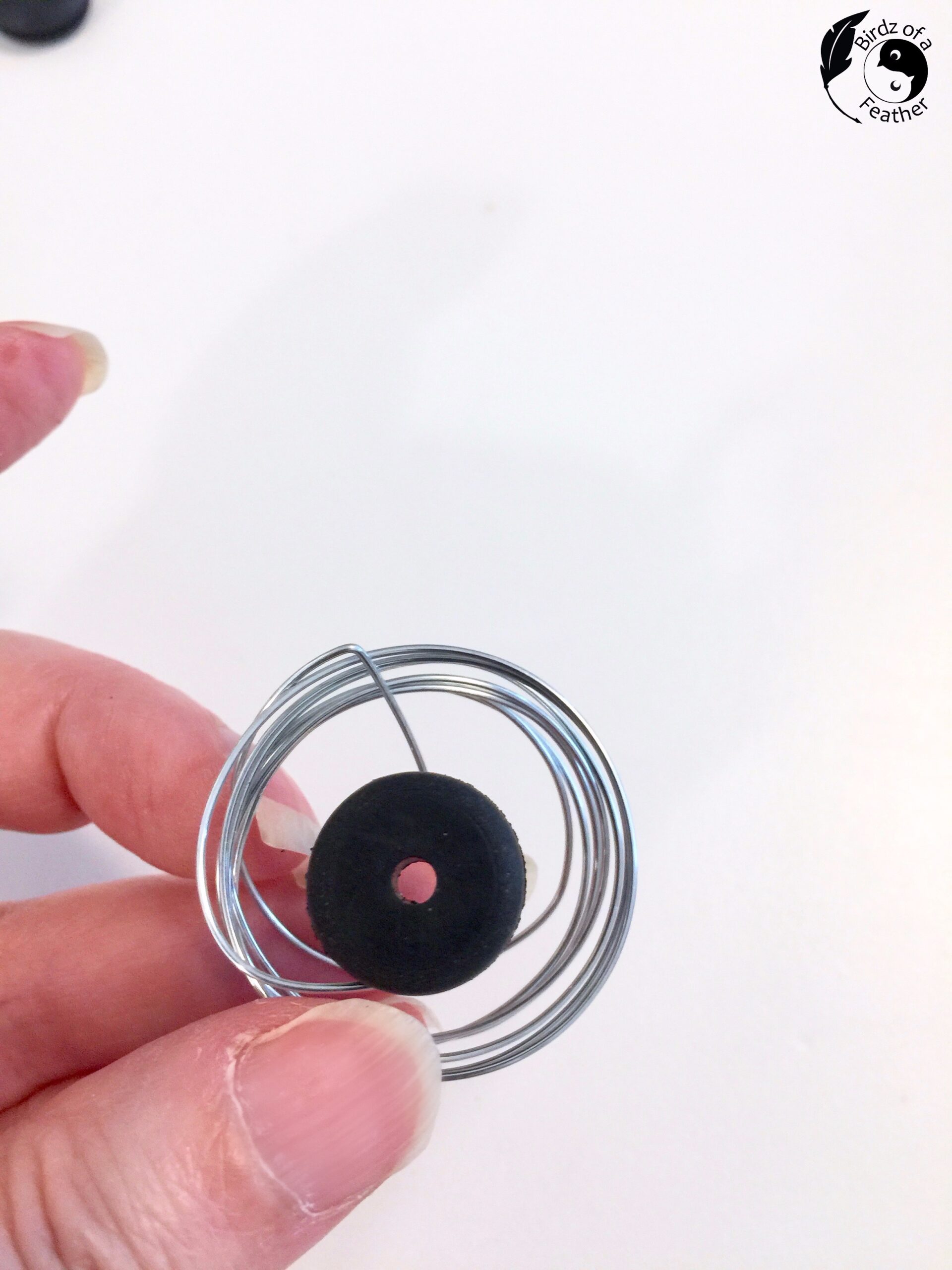 Fingers pinching together wire coil with grommet in the centre