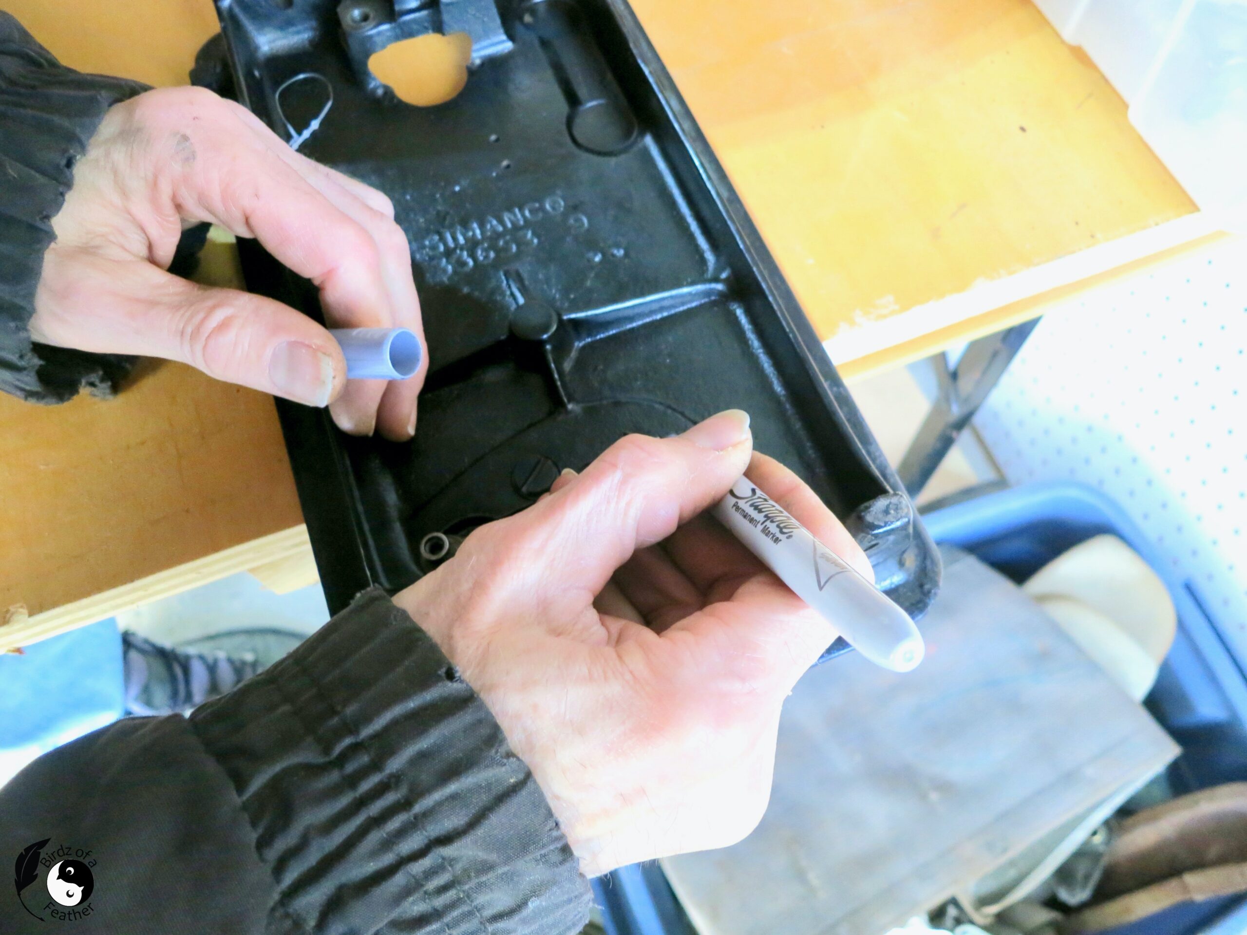 Silver marker being put onto the bolt onto the bottom of the sewing machine