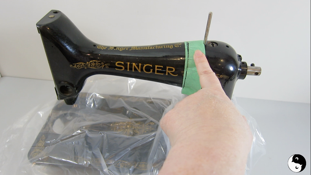 Finger pointing to straight line on green tape wrapped around sewing machine before cutting for DIY bookends