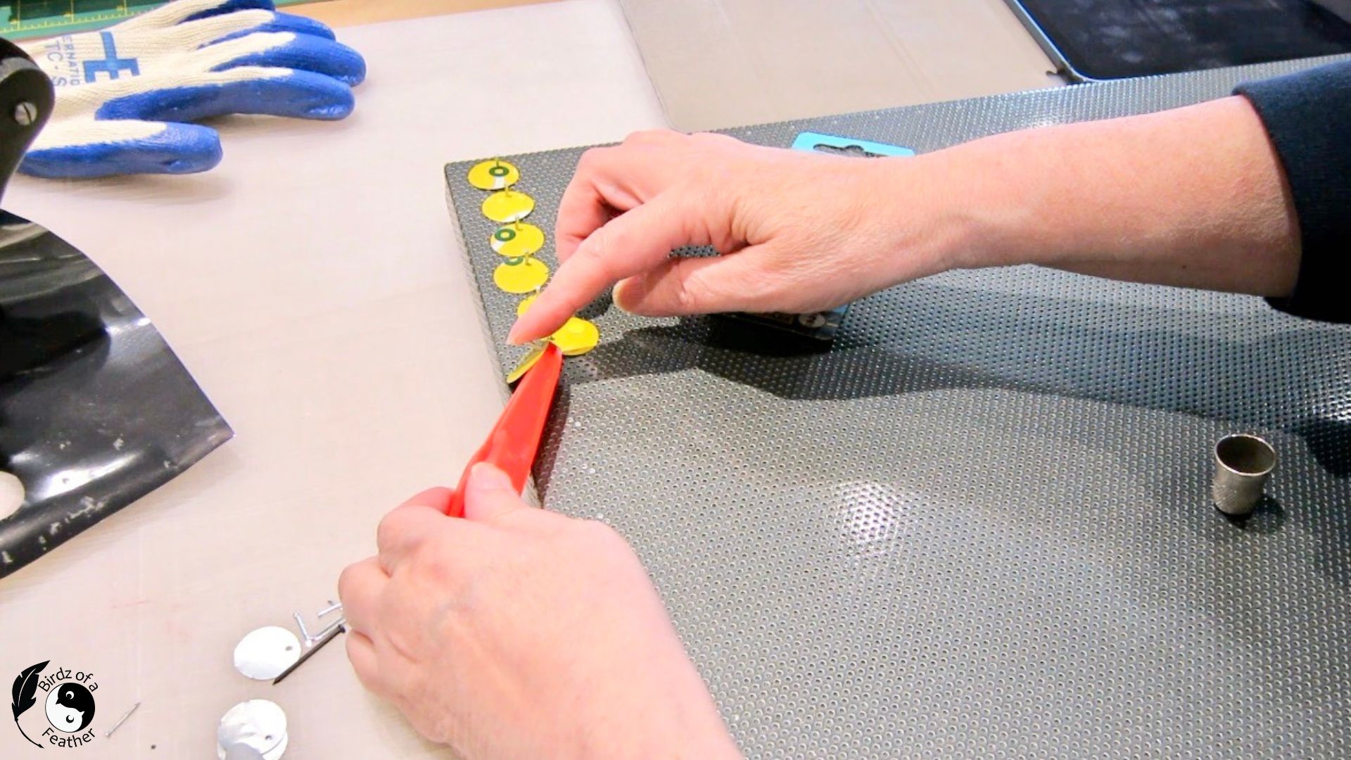 Hand positioning the circle punches over the message board for soda can craft