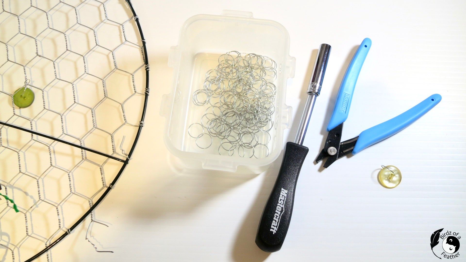 Jump rings in plastic container on table with suncatcher DIY and tools