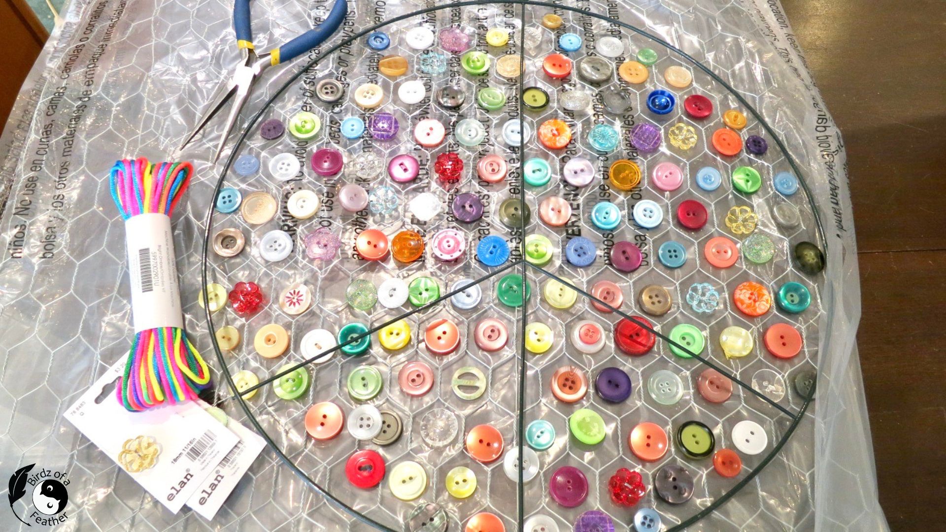 Buttons laid out on chicken wire and peace sign for suncatcher DIY
