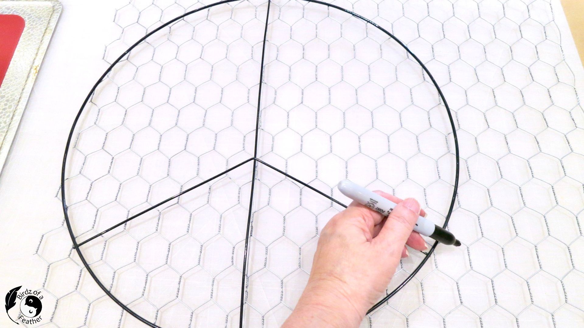 Marking around the peace sign on the chicken wire with a Sharpie