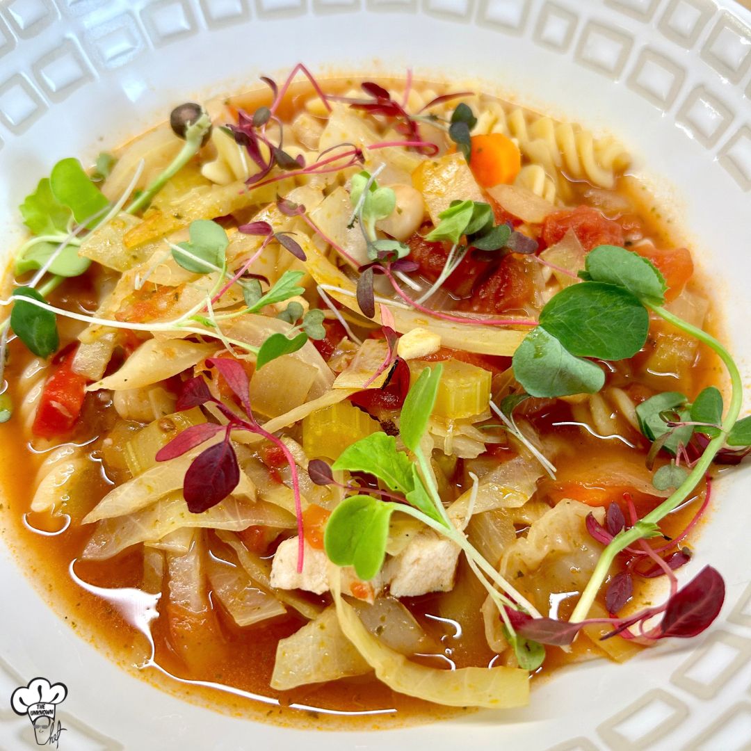 vegetable cabbage soup in a bowl garnished with micro greens