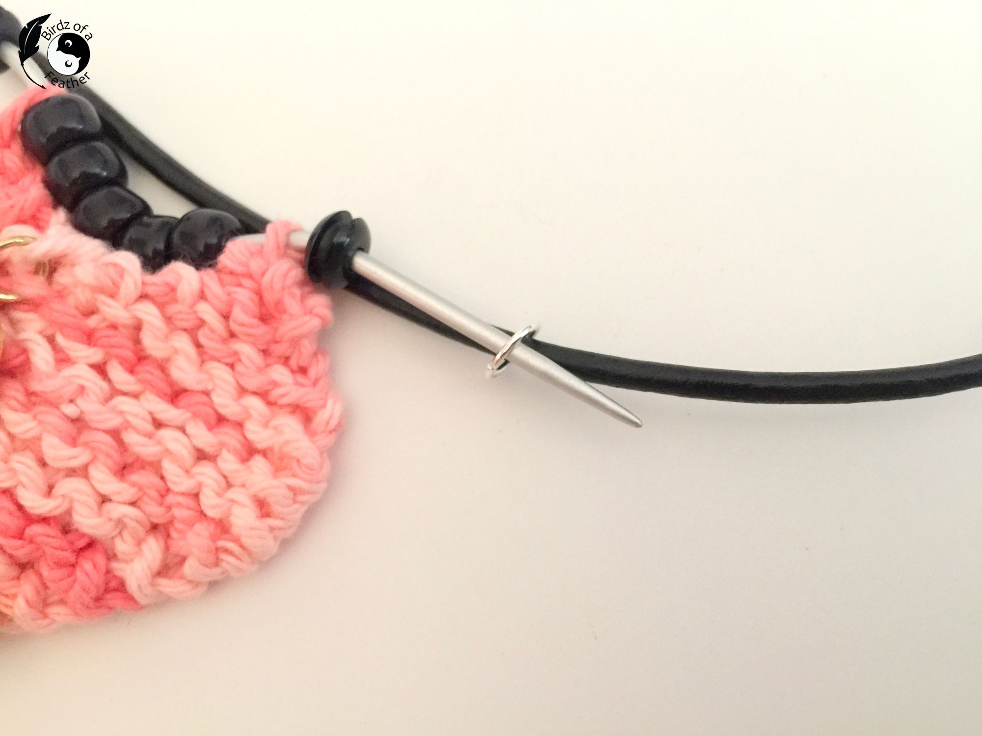 Knitting needle inserted into jump ring on leather cord of DIY Charm Necklace